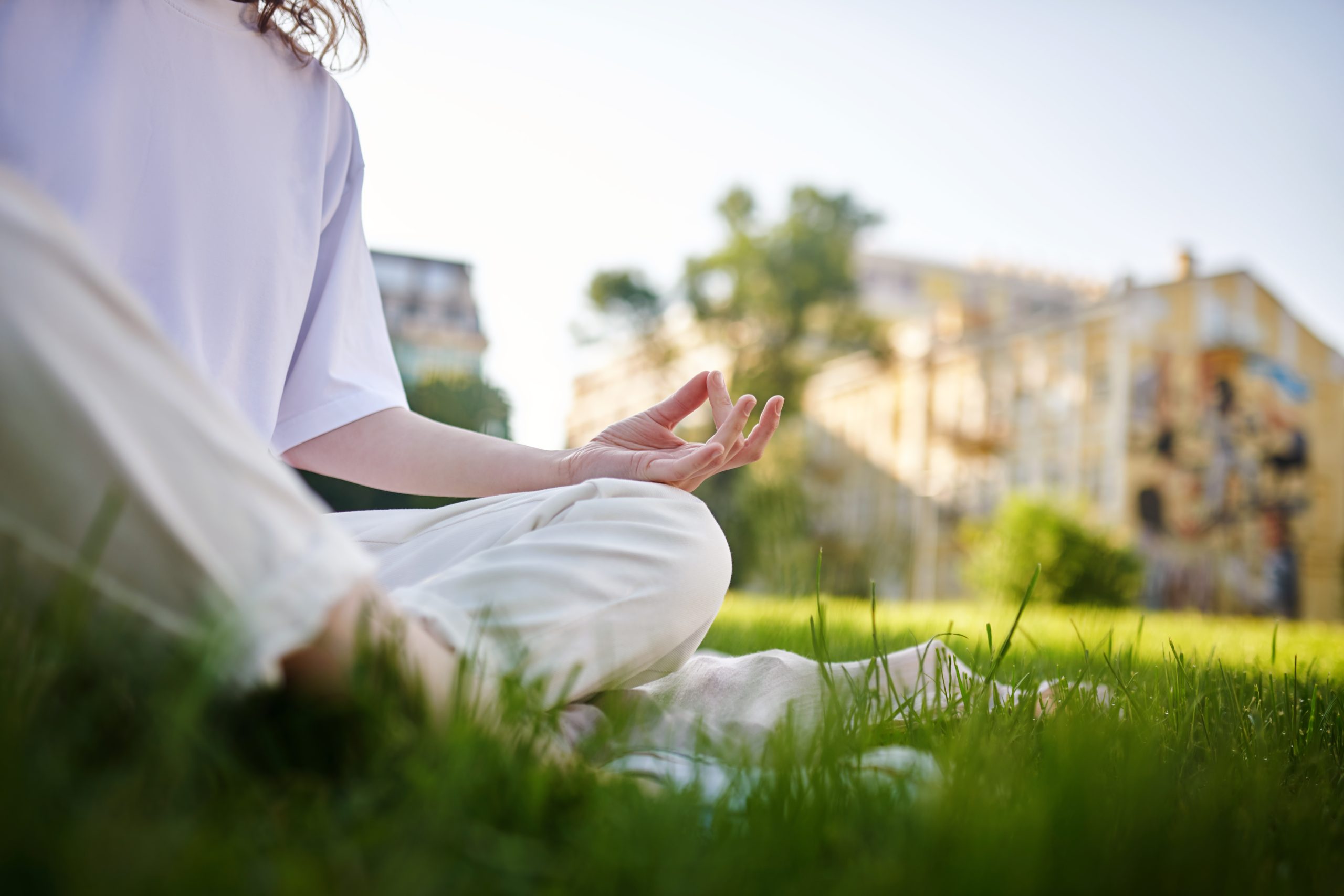 A girl in white meditating in the park and looking peaceful