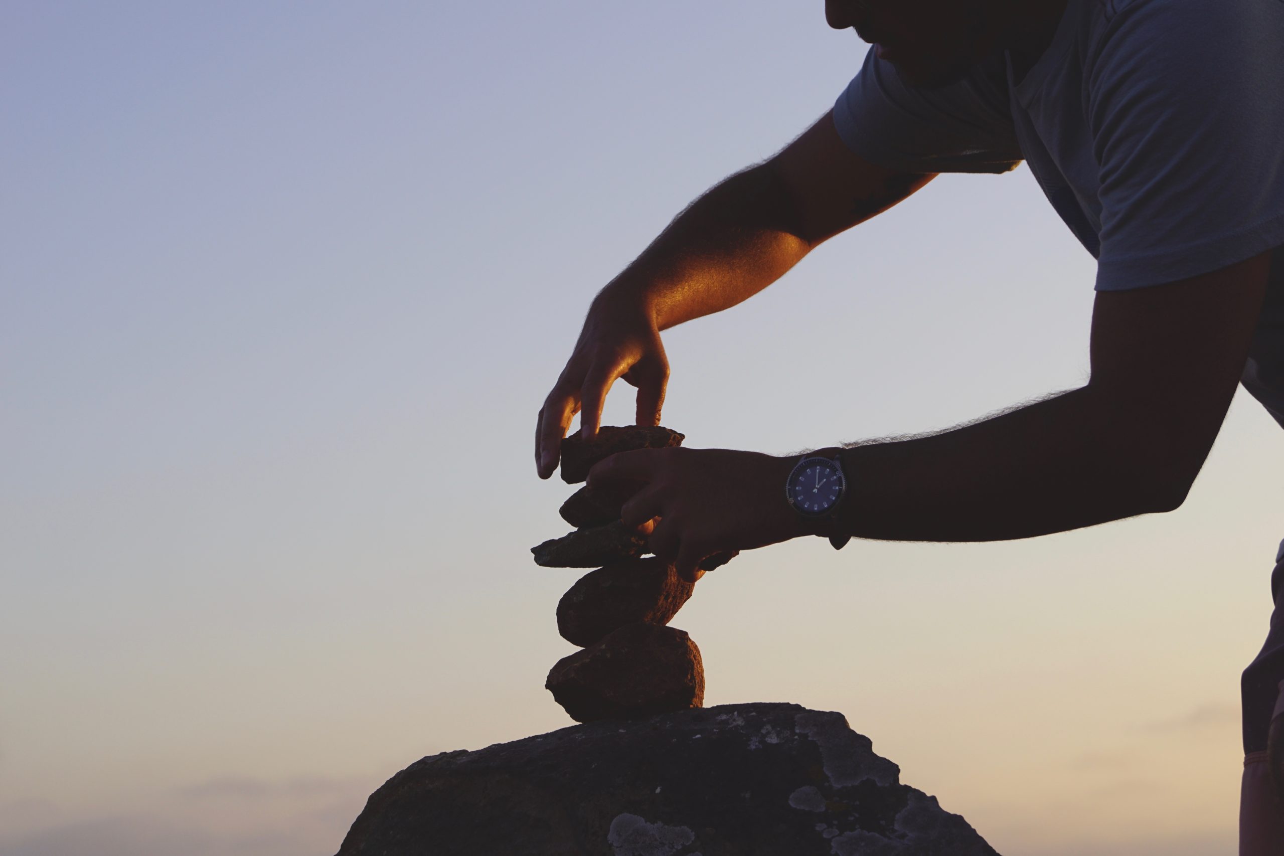 man-stacking-rocks-at-sunset-for-balance-2026-01-09-01-20-56-utc